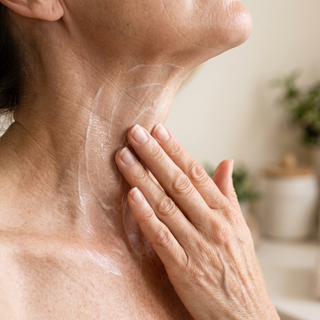 Hand applying cream upward on the neck