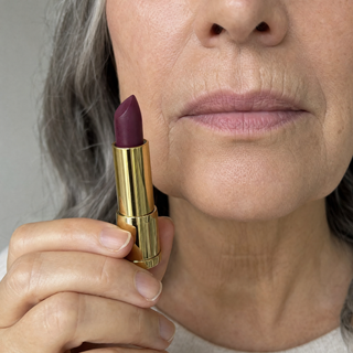 Bullet color held beside bare lips