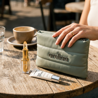 Areliaa Puffer Pouch on a cafe table with Areliaa lipstick and gloss